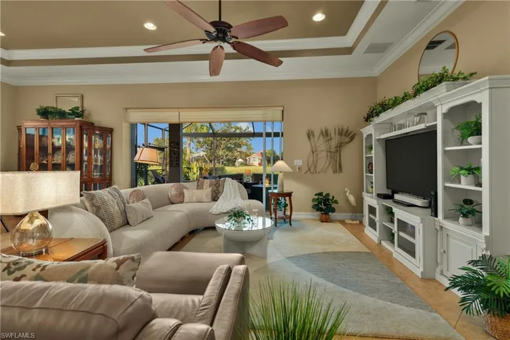 Living room with ceiling fan, ornamental molding, and a tray ceiling