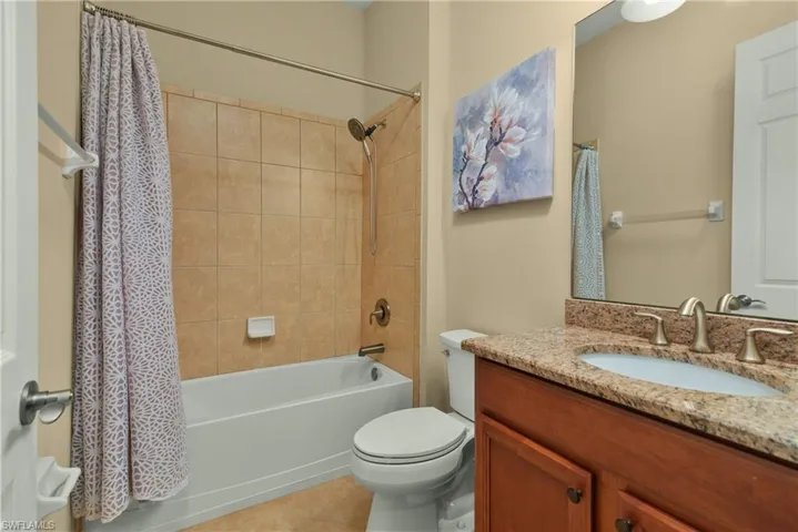 Full bathroom with tile patterned flooring, shower / bath combo, toilet, and vanity