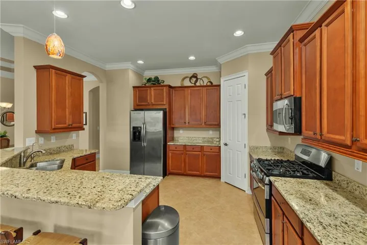 Kitchen featuring a kitchen bar, ornamental molding, stainless steel appliances, sink, and pendant lighting