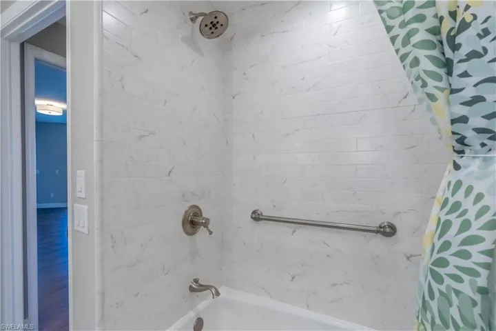 Guest bathroom showcasing tub/shower combo and hand hold