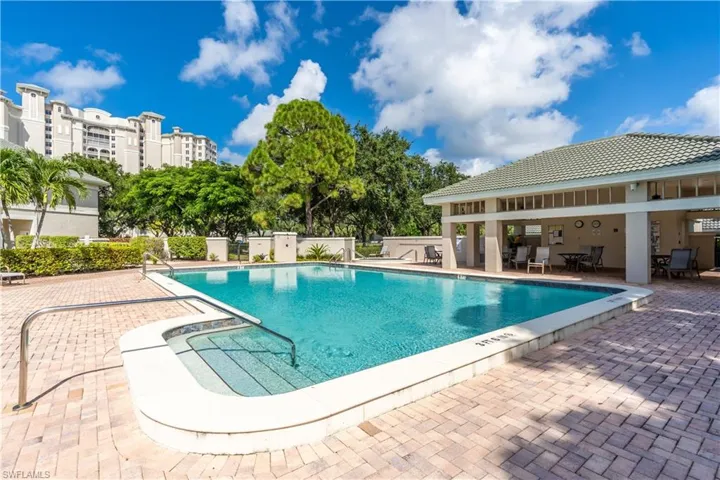 View of community pool featuring covered and uncovered lounge areas.