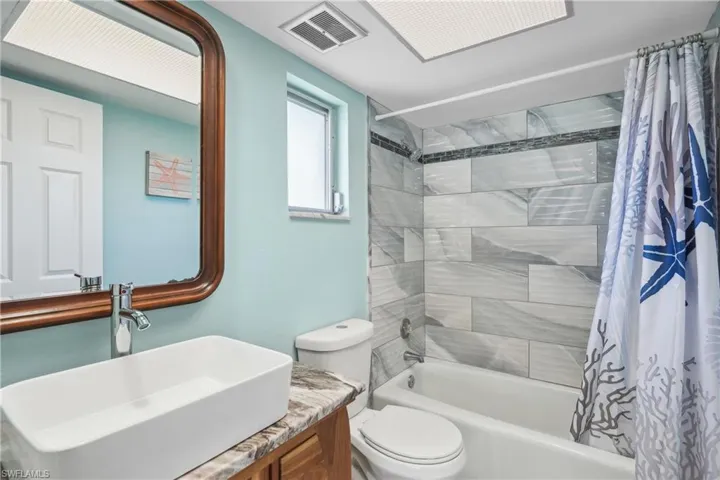 Full bathroom with vanity, toilet, and shower / bathtub combination with curtain
