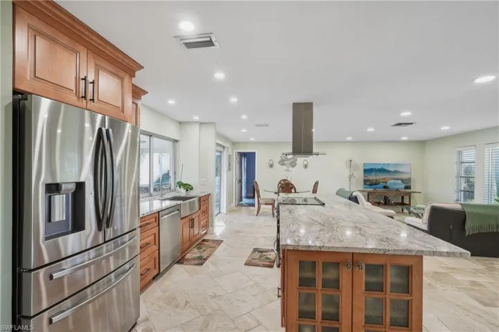 Kitchen with sink, a kitchen island, light stone countertops, island range hood, and stainless steel appliances