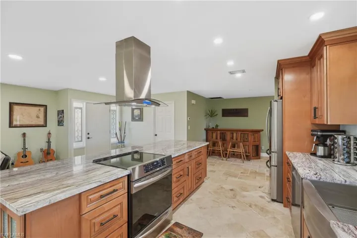 Kitchen featuring island range hood, a center island, stainless steel appliances, and light stone counters