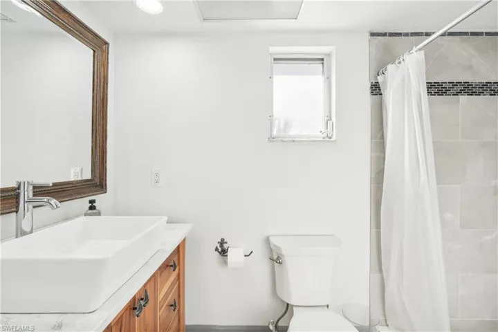 Bathroom featuring a shower with shower curtain, vanity, and toilet