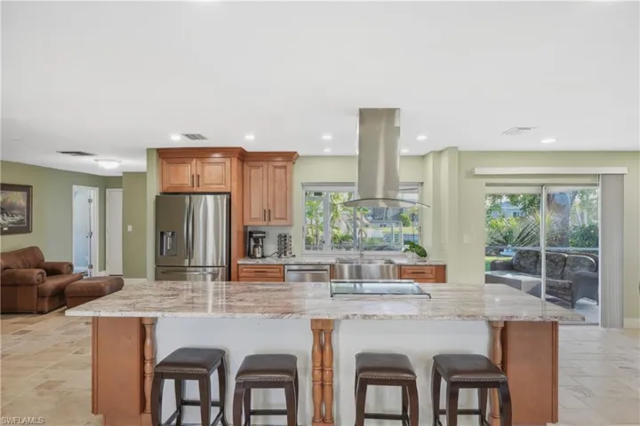 Kitchen with a large island, island range hood, a kitchen bar, and stainless steel appliances