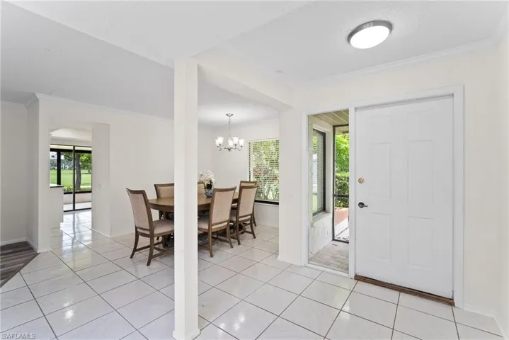 Tiled dining area with a notable chandelier, crown molding, and plenty of natural light