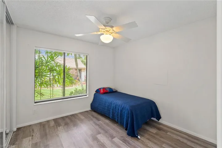 Bedroom with a textured ceiling, ceiling fan, and hardwood / wood-style floors