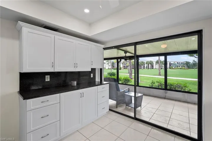 Kitchen with white cabinets, light tile patterned flooring, tasteful backsplash, and a wealth of natural light