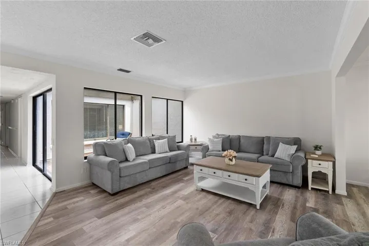 Living room with ornamental molding, hardwood / wood-style floors, and a textured ceiling