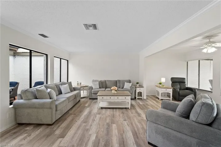 Living room with light hardwood / wood-style flooring, ceiling fan, and plenty of natural light