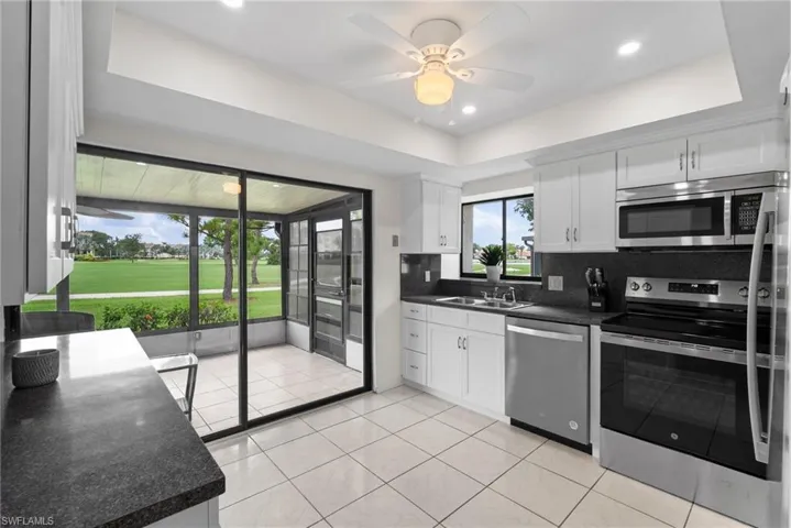 Kitchen with white cabinets, stainless steel appliances, a raised ceiling, and tasteful backsplash