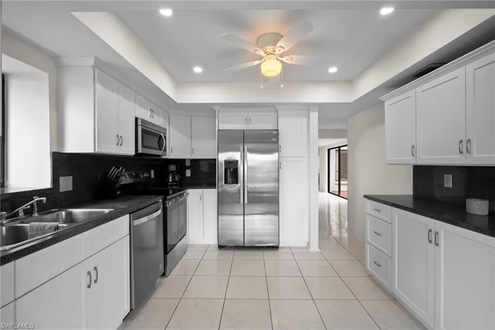 Kitchen featuring stainless steel appliances, a raised ceiling, tasteful backsplash, and ceiling fan