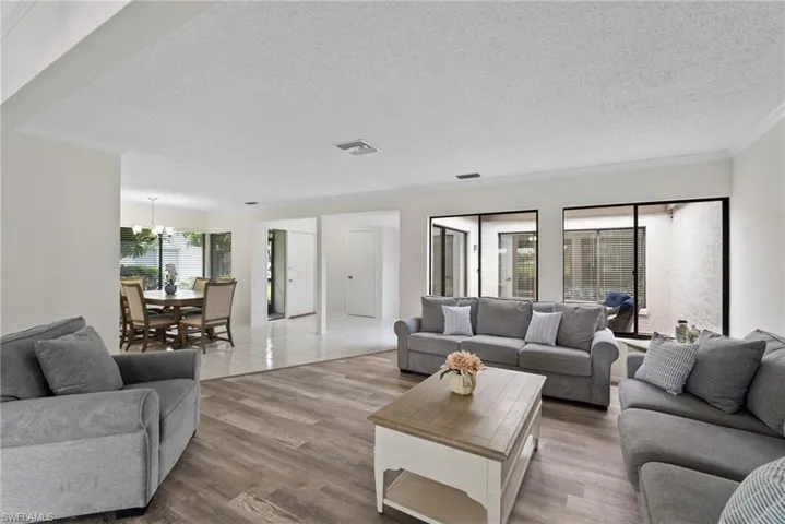 Living room with hardwood / wood-style flooring, a textured ceiling, ornamental molding, and an inviting chandelier