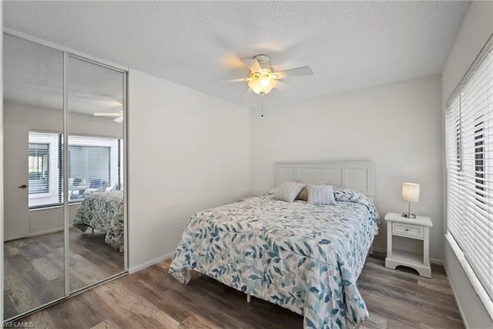Bedroom with a textured ceiling, ceiling fan, wood-type flooring, and a closet