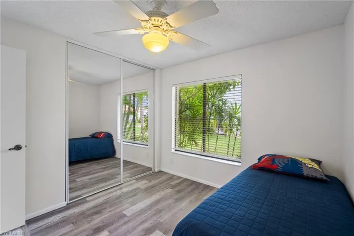 Bedroom with a textured ceiling, ceiling fan, wood-type flooring, and a closet