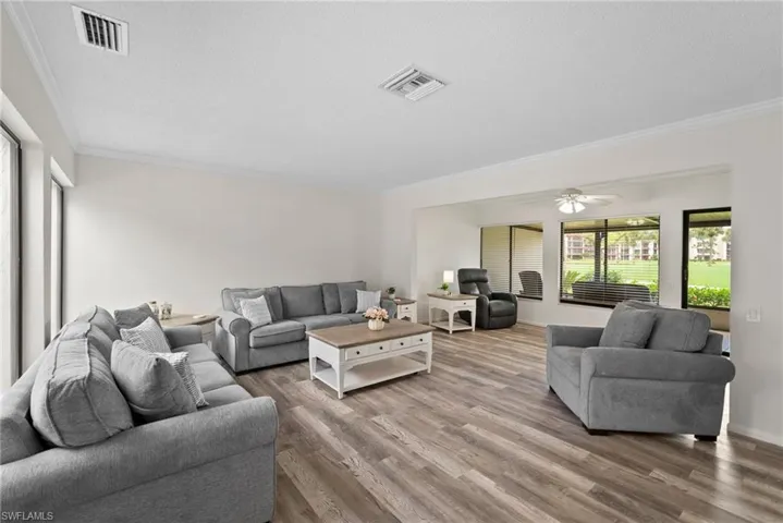 Living room with a textured ceiling, crown molding, hardwood / wood-style floors, and ceiling fan
