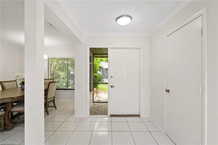 Foyer entrance featuring light tile patterned flooring, crown molding, and plenty of natural light