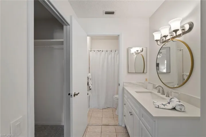 Bathroom with vanity, tile patterned flooring, toilet, and a textured ceiling