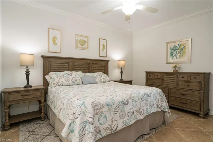 Tiled primary bedroom featuring upgraded ceiling fan and crown molding.