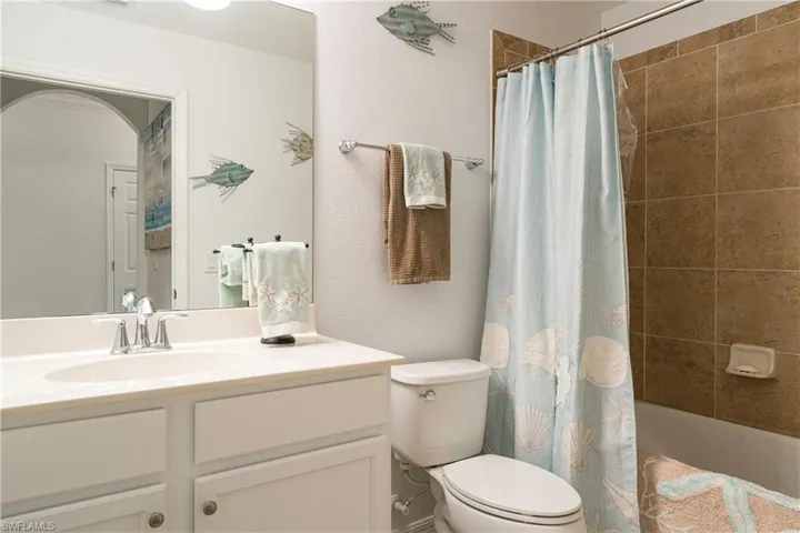 Full bathroom with newly painted vanity, toilet, and shower / tub combo with curtain