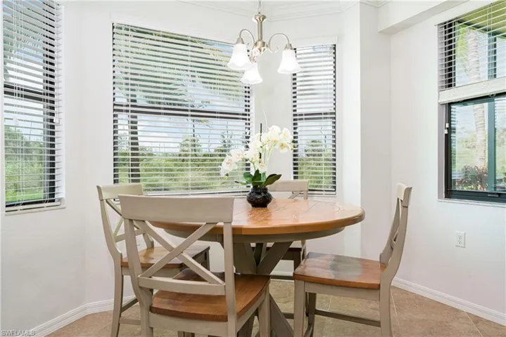 Dining room with crown molding, a notable chandelier, and light tile patterned flooring.