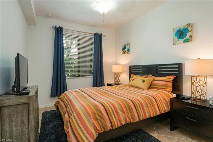 Bedroom with ceiling fan and tile patterned flooring.