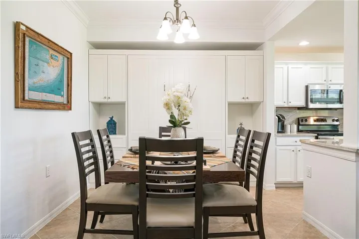 Dining space featuring crown molding, a chandelier, and light tile patterned flooring.