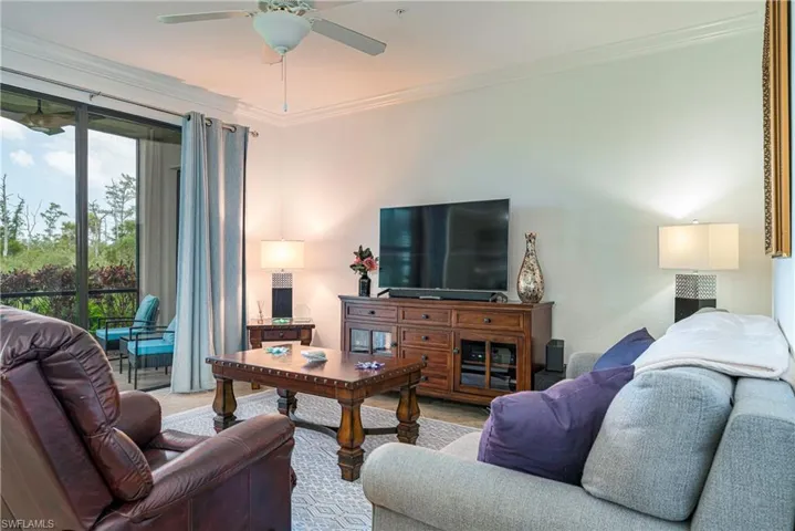 Living room featuring ornamental molding, light carpet, and upgraded ceiling fan