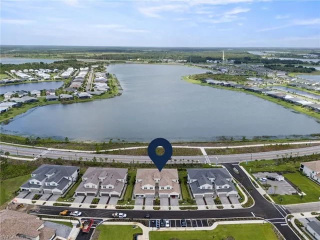 Aerial view of property and surrounding area featuring a nearby body of water and nearby suburban area
