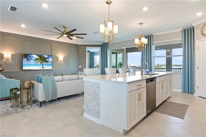 Kitchen featuring a chandelier, open floor plan, ornamental molding, light countertops, and white cabinets