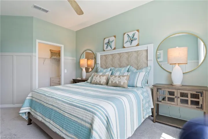 Bedroom with carpet floors, a ceiling fan, wainscoting, a spacious closet, and a decorative wall