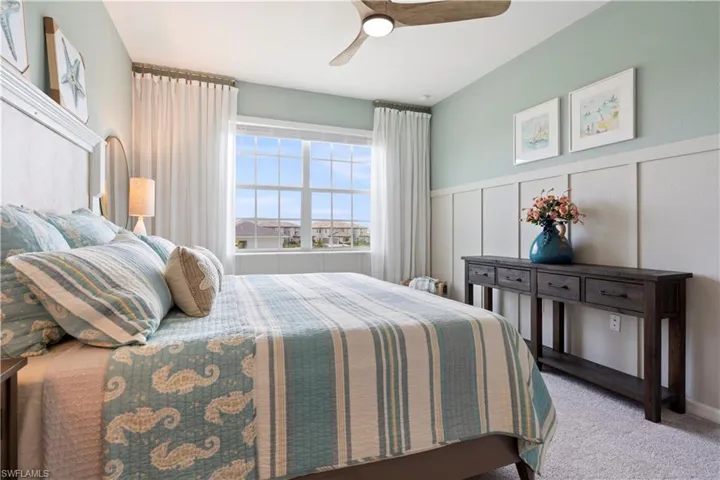 Bedroom with a decorative wall, carpet flooring, wainscoting, and ceiling fan