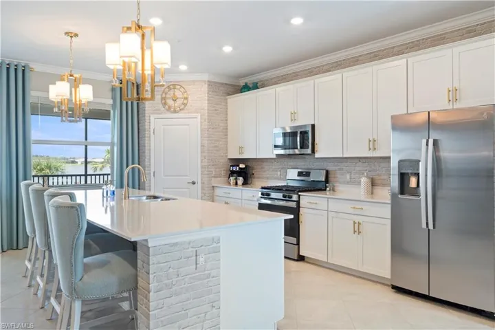 Kitchen featuring stainless steel appliances, a chandelier, light tile patterned floors, crown molding, and tasteful backsplash