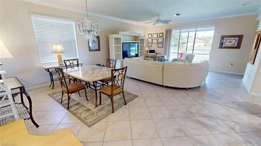 Dining room with ornamental molding, light tile patterned floors, a chandelier, and ceiling fan