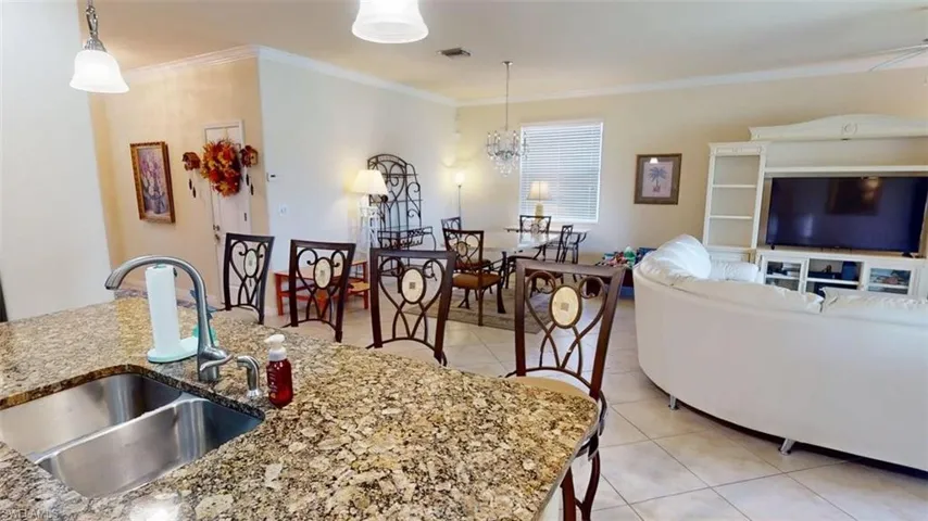 Dining room featuring light tile patterned flooring, crown molding, and a chandelier