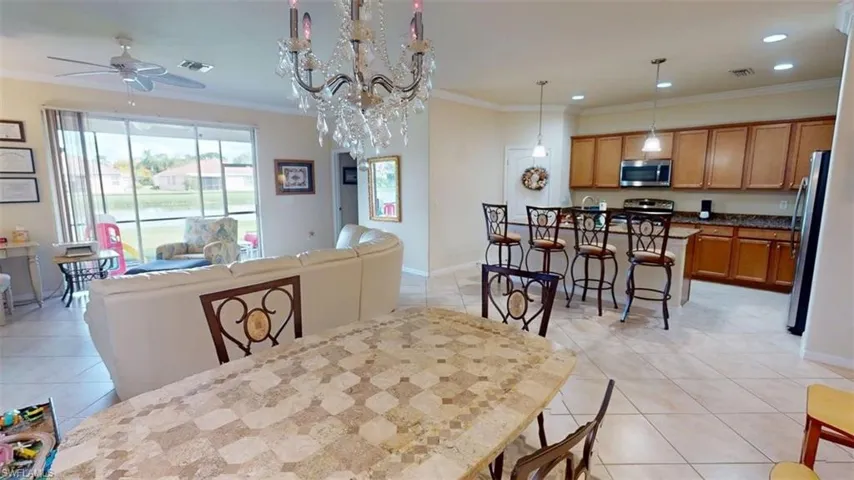 Dining space with crown molding, a chandelier, ceiling fan, light tile patterned floors, and recessed lighting