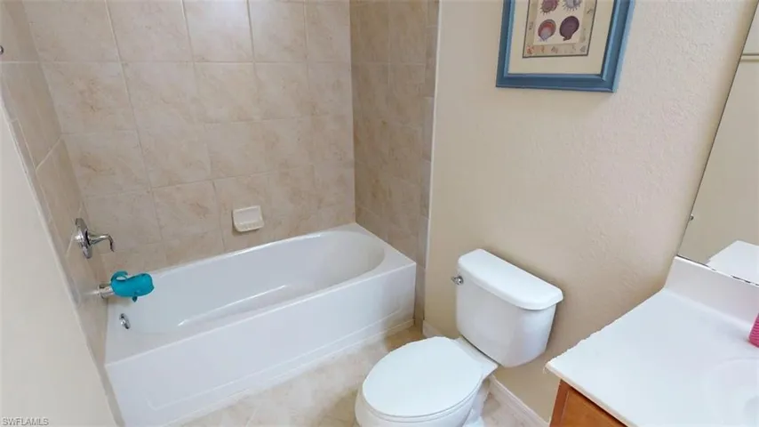 Bathroom with vanity, tub / shower combination, and a textured wall