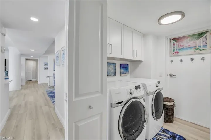 Washroom with washer and clothes dryer, light wood-type flooring, cabinet space, baseboards, and recessed lighting
