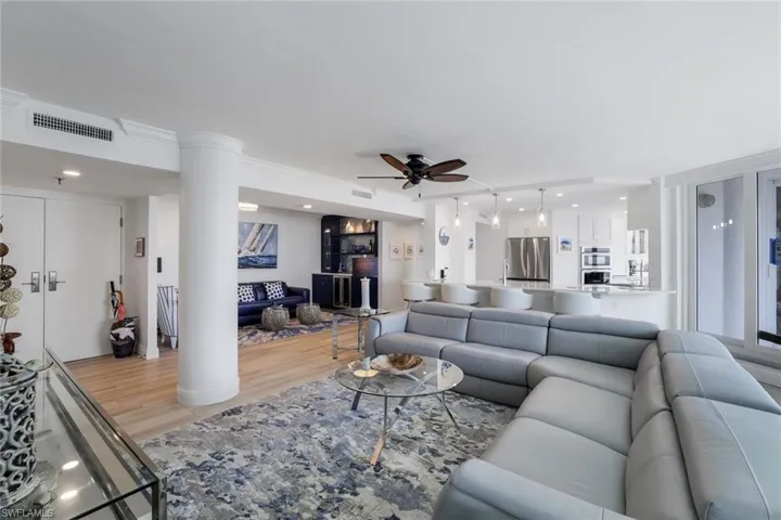 Living area with light wood finished floors, ceiling fan, ornate columns, and recessed lighting
