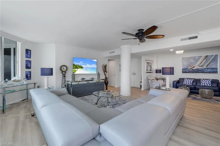 Living room featuring light wood-type flooring, a ceiling fan, and ornamental molding