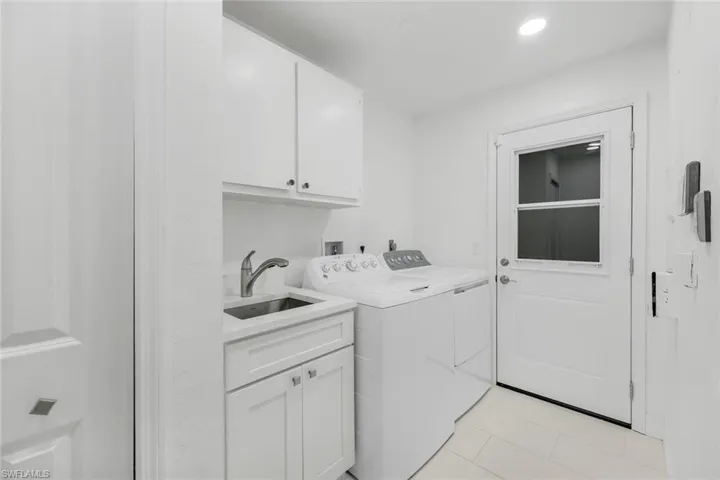 Laundry room featuring light tile patterned floors, independent washer and dryer, cabinets, and sink