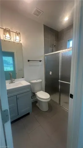 Full bath featuring vanity, a shower stall, dark tile patterned flooring, and plenty of natural light