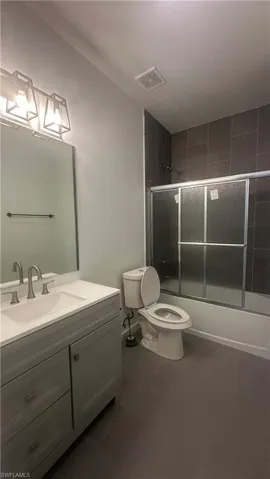 Bathroom featuring vanity and bath / shower combo with glass door