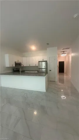 Kitchen with white cabinets, stainless steel appliances, and dark stone countertops