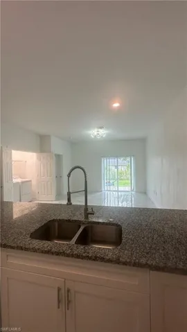 Kitchen featuring dark stone counters, recessed lighting, white cabinets, and washer and clothes dryer