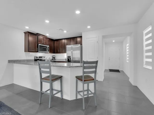 Kitchen featuring light stone counters, a breakfast bar area, appliances with stainless steel finishes, a peninsula, and recessed lighting
