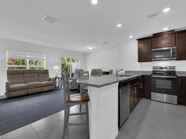 Kitchen featuring visible vents, appliances with stainless steel finishes, a sink, a kitchen breakfast bar, and light tile patterned floors