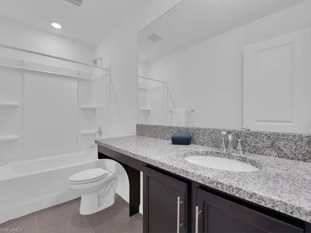 Full bath featuring tile patterned flooring, vanity, shower / tub combination, and toilet