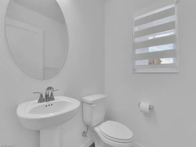 Half bathroom with toilet, a sink, and baseboards